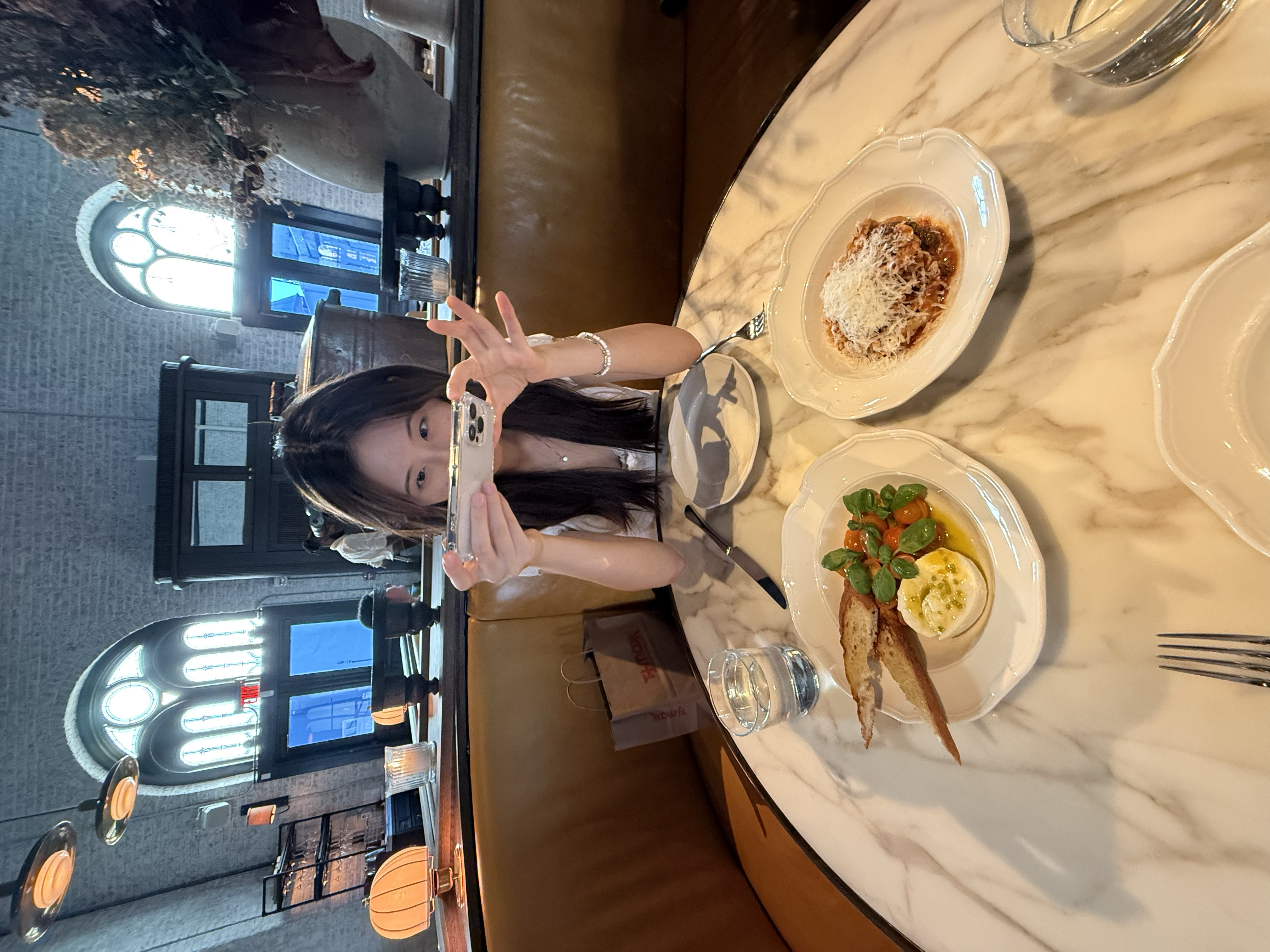 Ashley photographing a pasta dinner at a restaurant table