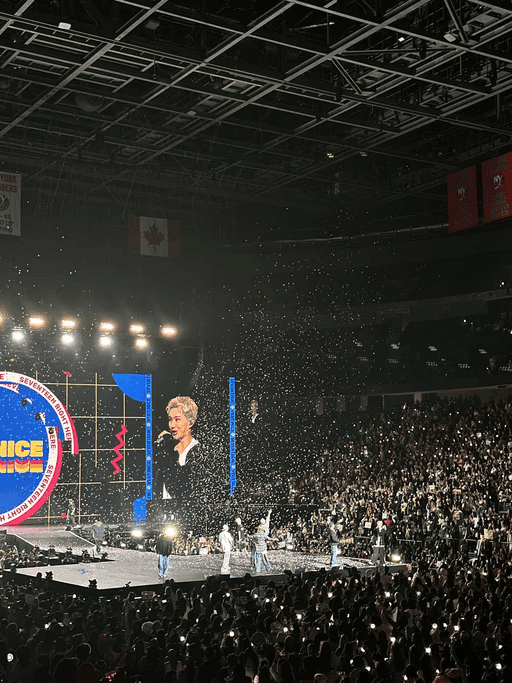 A concert crowd with confetti falling under stage lights