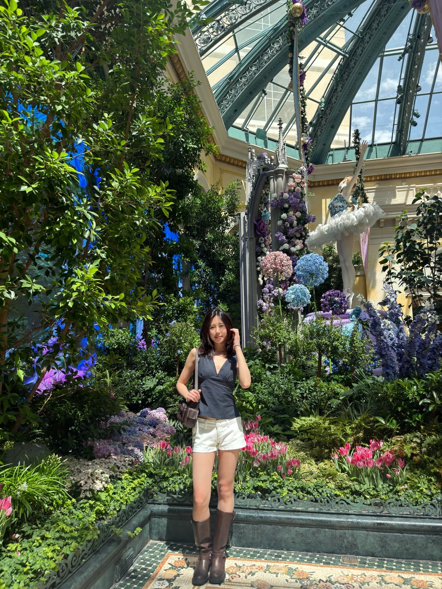Portrait of Ashley in a glass-domed botanical garden surrounded by flowers